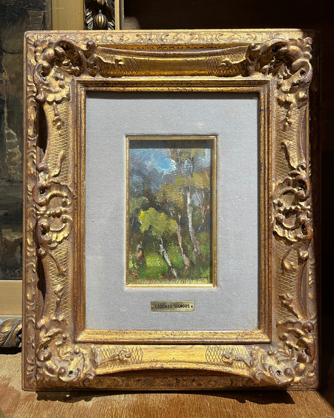 19th-Century Oil Painting by Lorenzo Gignous in a period giltwood frame with a velvet mat and brass nameplate, depicting a woodland scene with sunlight filtering through trees.