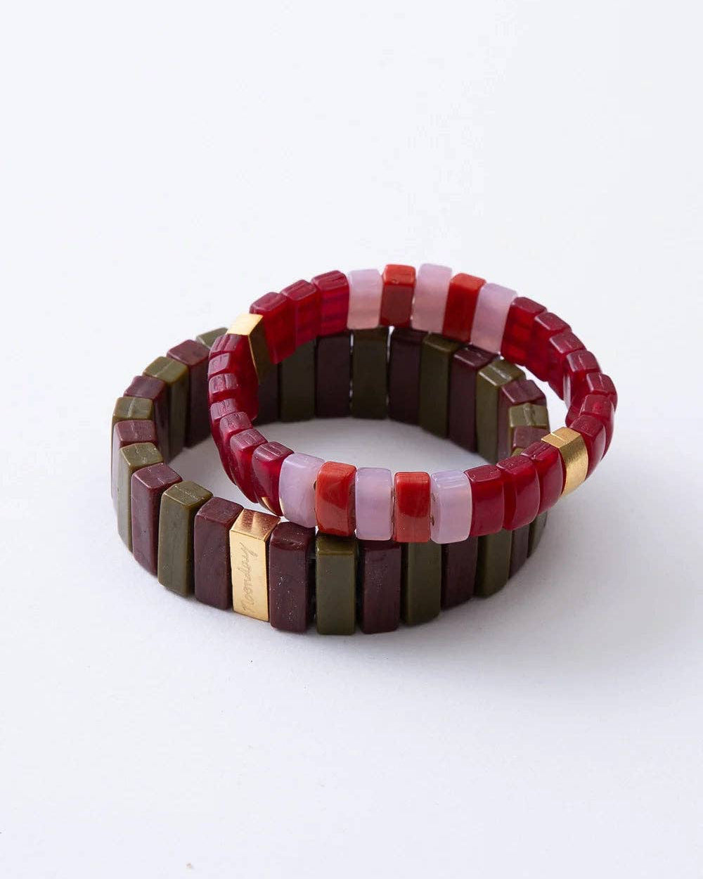 Two beaded stretch bracelets stacked together on a white background. One bracelet features alternating red and light pink translucent beads, while the other features alternating olive green and dark brown translucent beads with small gold spacer accents.