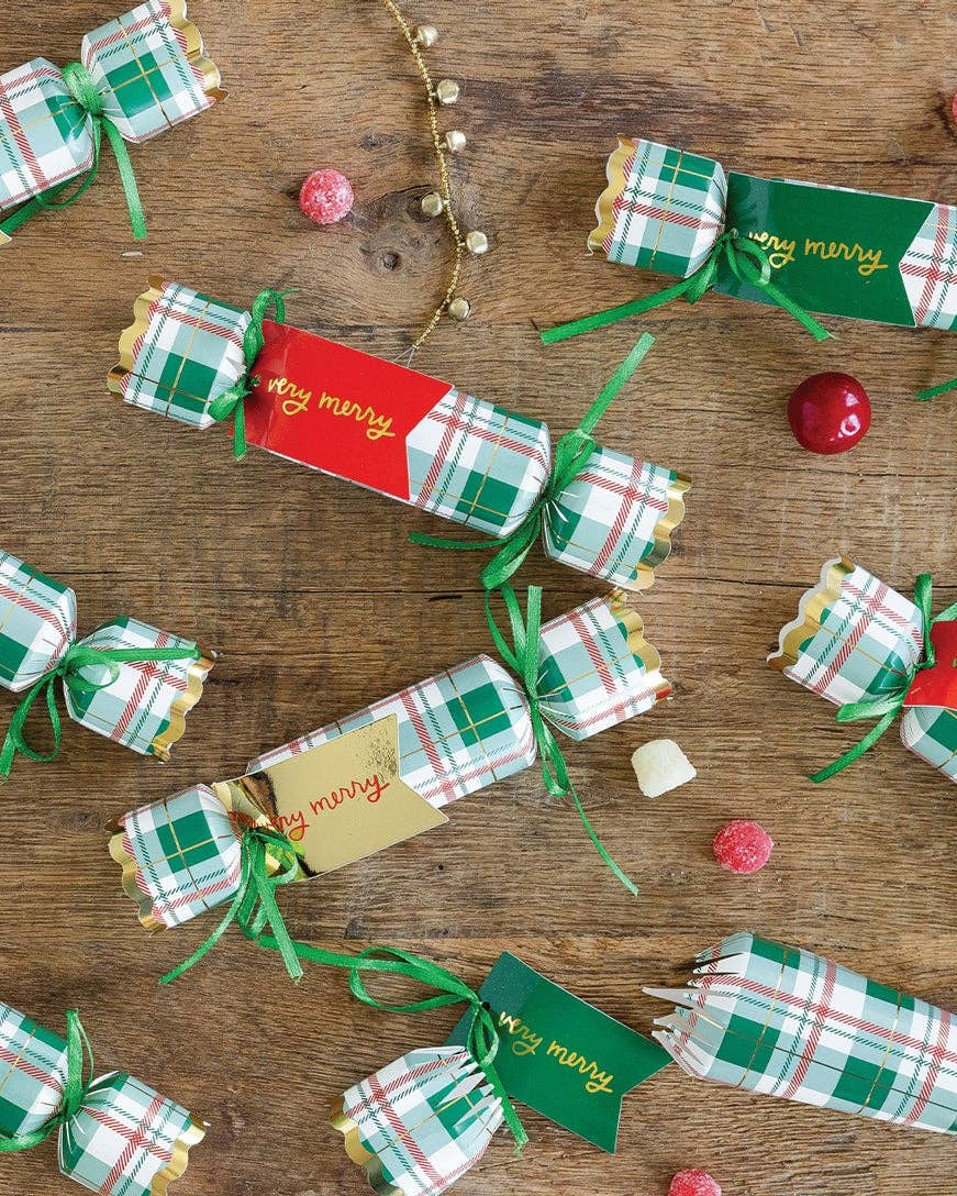 Decorative Christmas cracker boxes on a wooden surface with small red and gold balls.