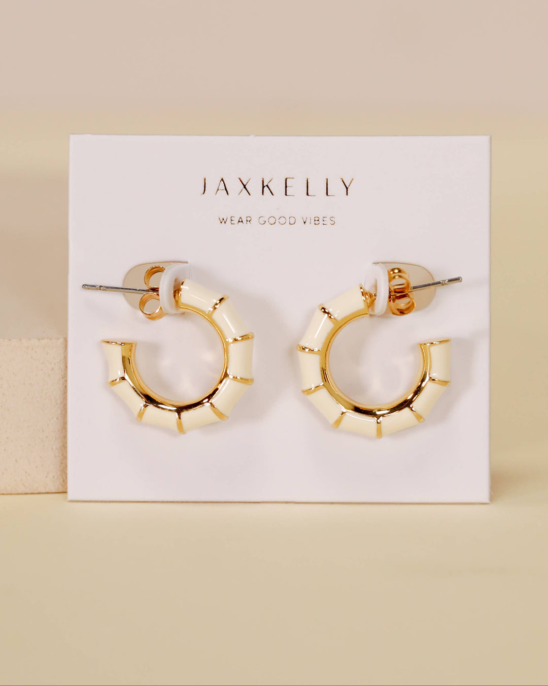 Gold hoop earrings on a Jaxkelly branded card against a beige background