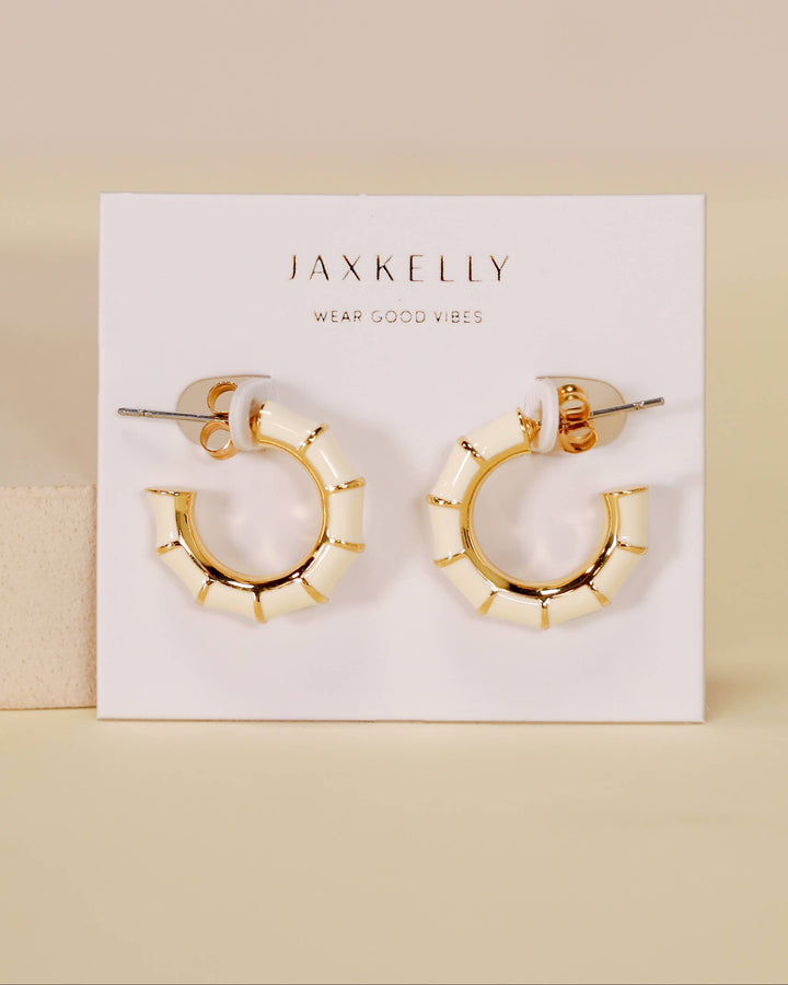 Gold hoop earrings on a Jaxkelly branded card against a beige background