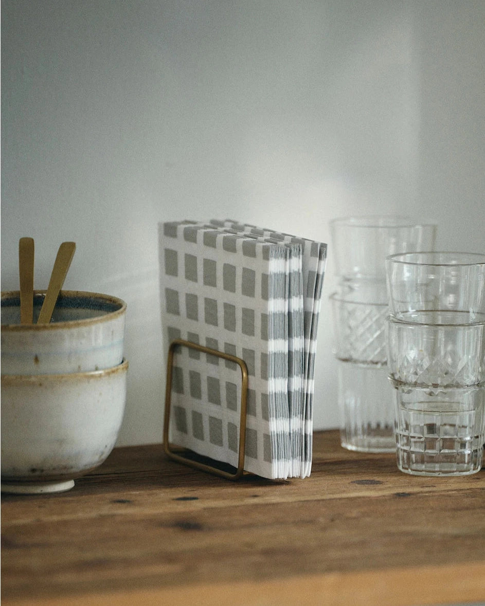 Kitchen counter with a bowl, checkered towel, and glasses on a wooden surface.