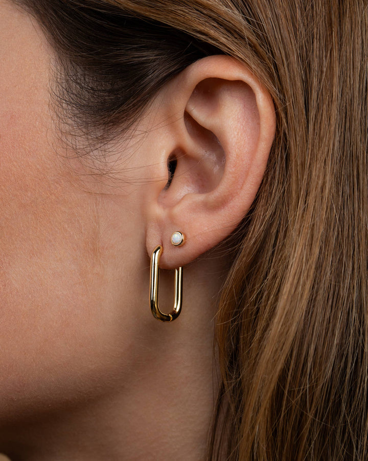 Close-up of a person wearing a gold hoop earring with a pearl accent.