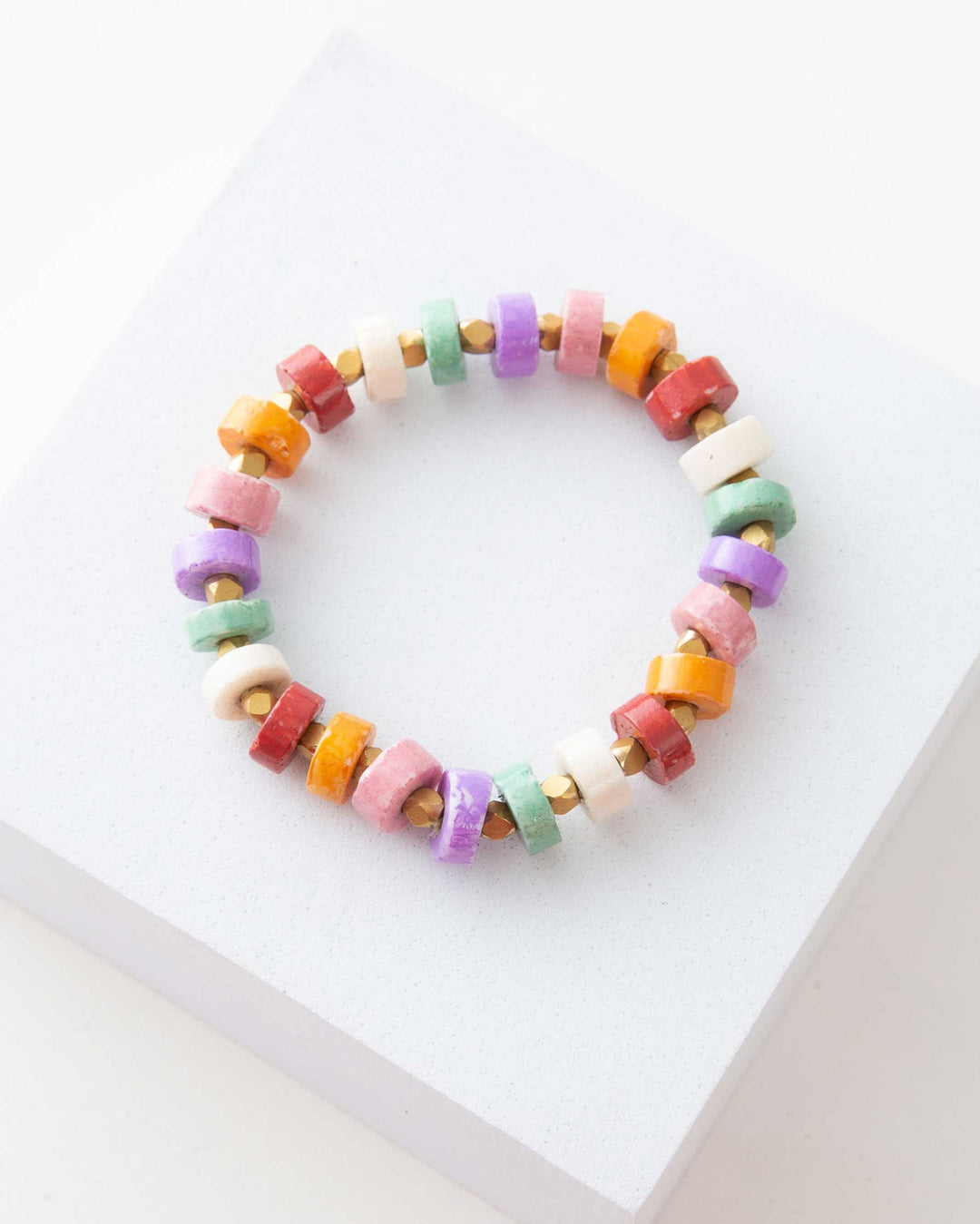 A multicolored bracelet with pastel hued discs, displayed on a white surface.