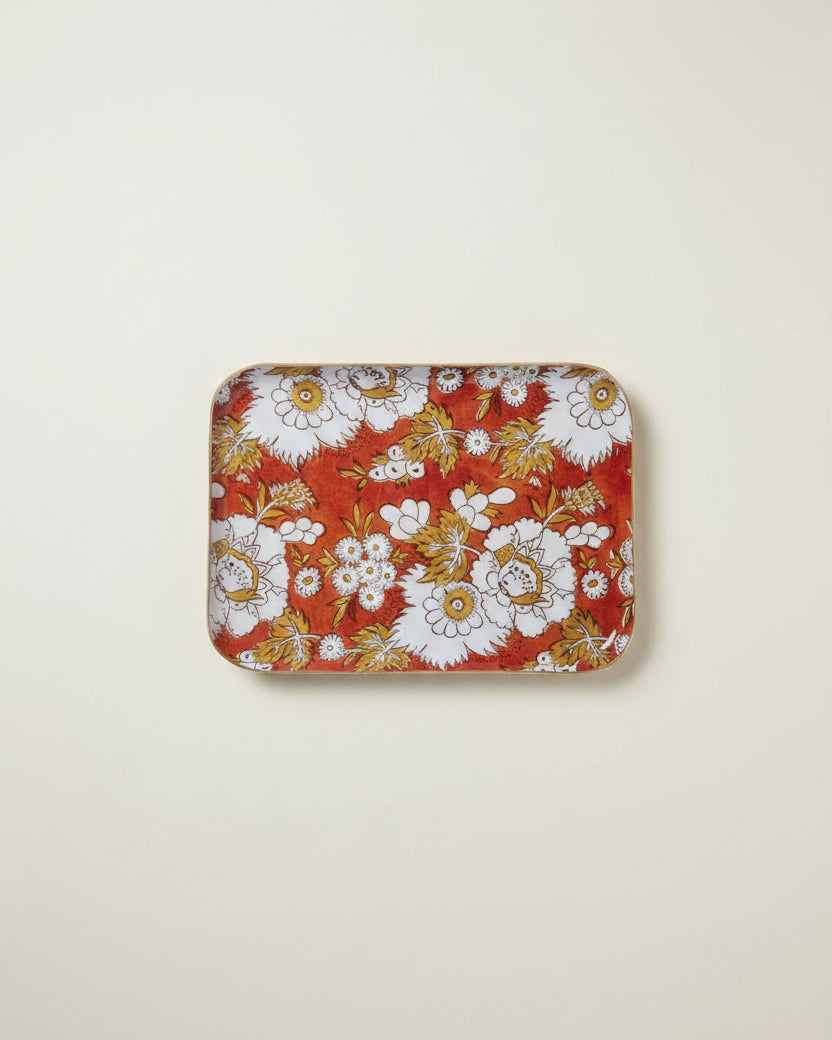 A rectangular tray with rounded corners featuring a vibrant floral pattern on a terracotta red background, with white flowers and gold-toned leaves.
