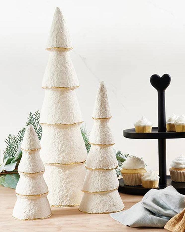 Decorative items including small trees, a bottle with a bow, and a stand with cupcakes on a light surface.