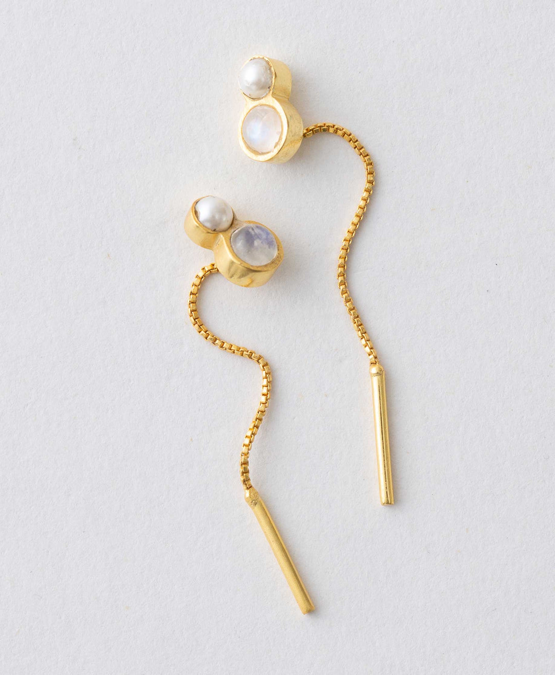 A pair of gold-colored threader earrings with moonstone accents, displayed against a neutral background.