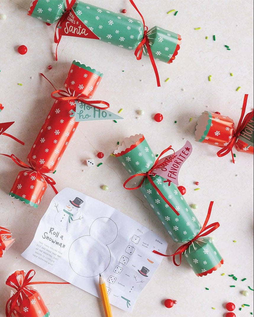 Red and green Christmas crackers on a white background with confetti.