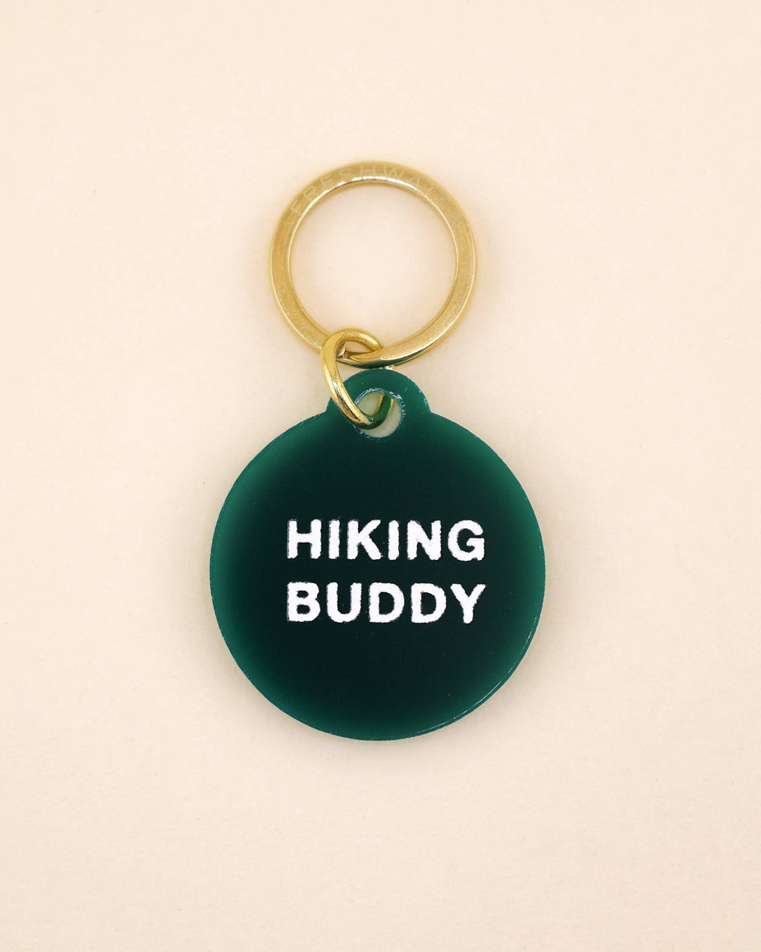 Green pet tag with 'Hiking Buddy' text on a beige background