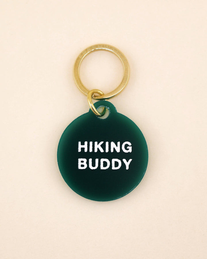 Green pet tag with 'Hiking Buddy' text on a beige background