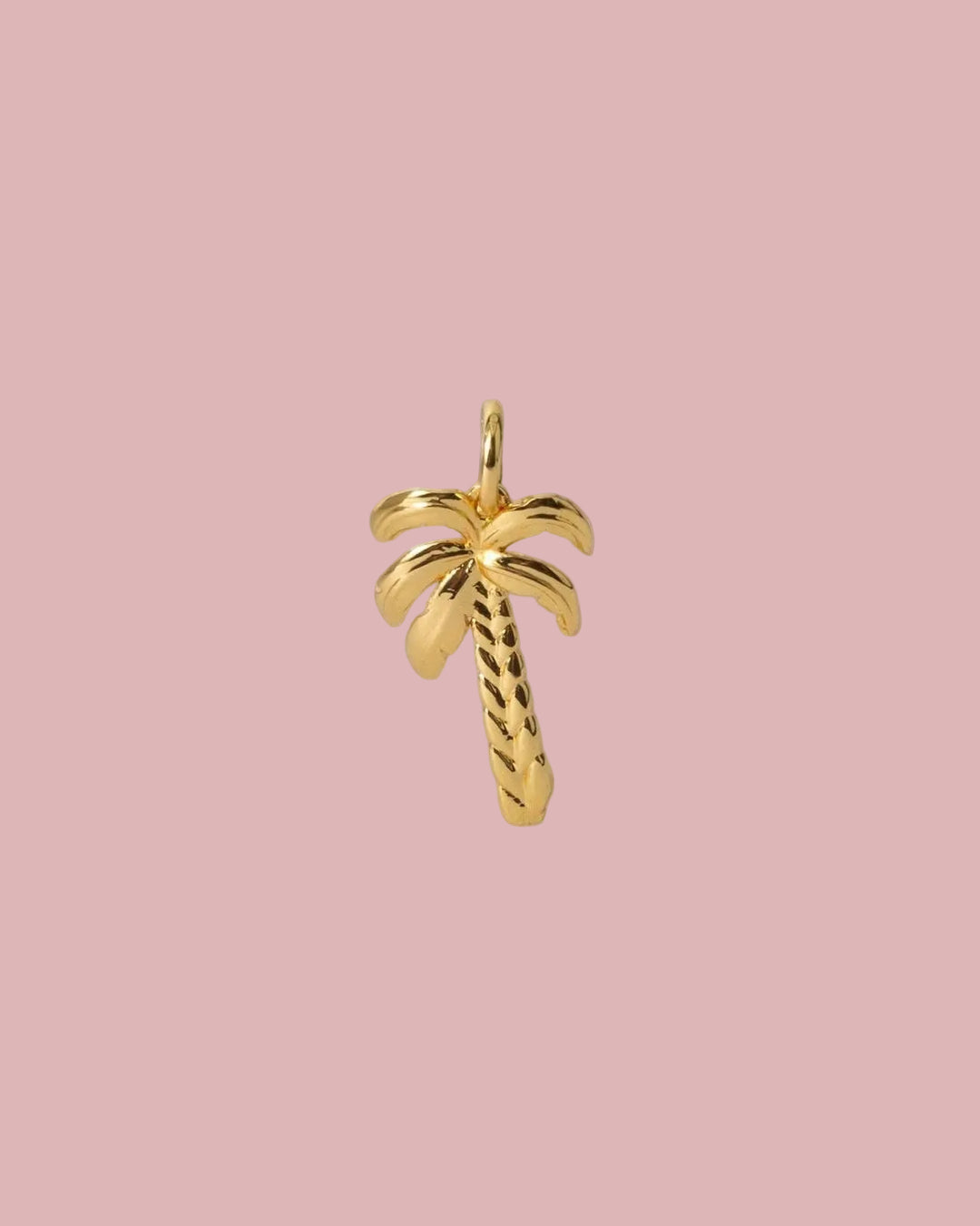 A small gold palm tree charm pendant with a textured trunk and a polished loop at the top, shown on a light gray background.