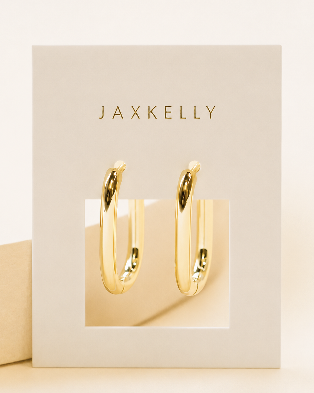 Gold hoop earrings in a Jaxkelly branded box on a beige background