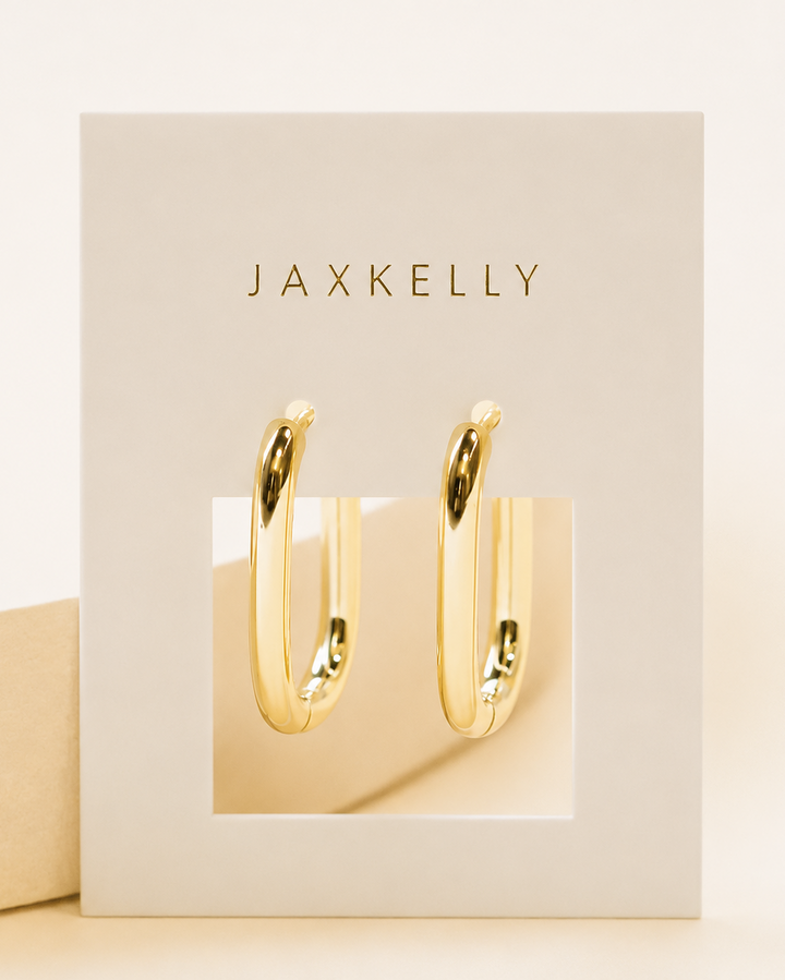 Gold hoop earrings in a Jaxkelly branded box on a beige background