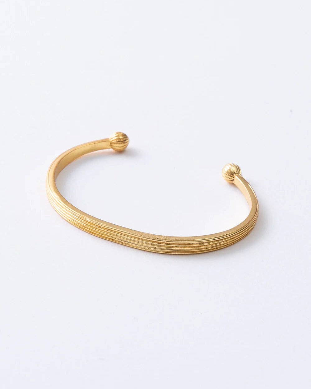 A gold-toned open cuff bangle bracelet with a textured, ridged surface and small ball details at the ends, displayed on a clean white background.