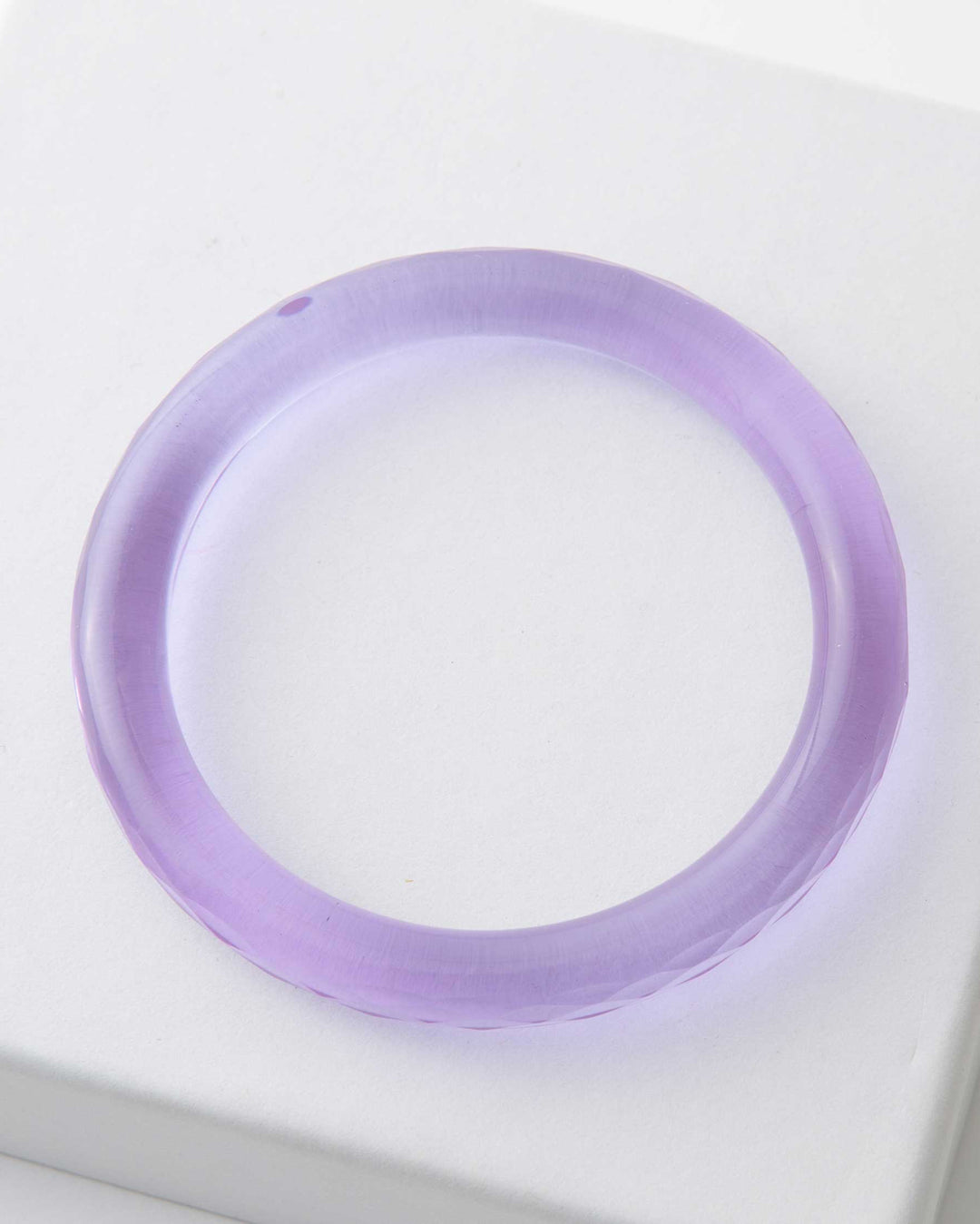 A single smooth purple glass bangle presented on a white surface.