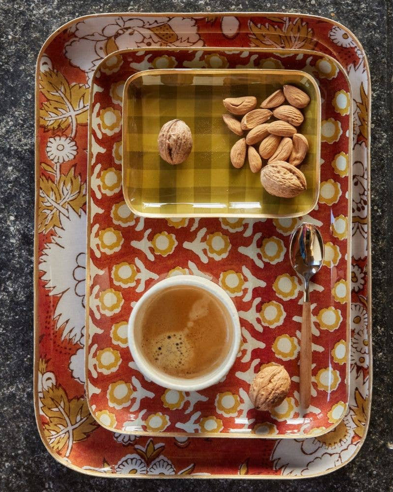 Decorative tray with a cup of coffee, nuts, and a spoon on a dark surface