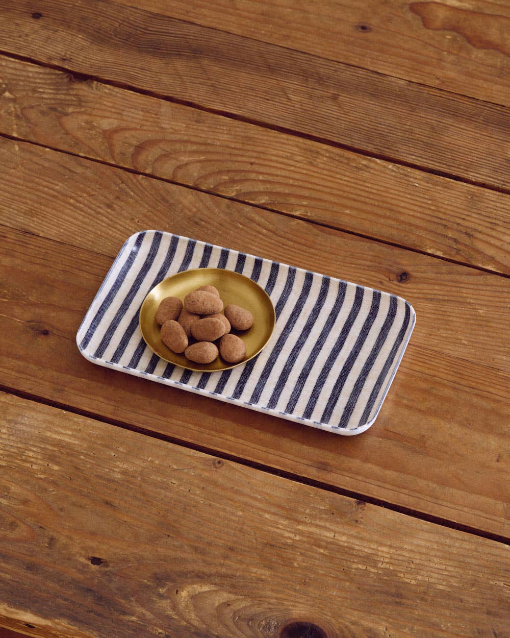 Rectangular striped tray with a gold bowl on a wooden surface