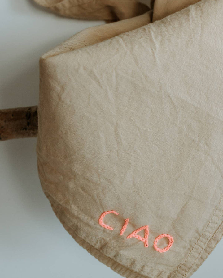 Beige fabric pouch with 'CIAO' embroidery on a white background