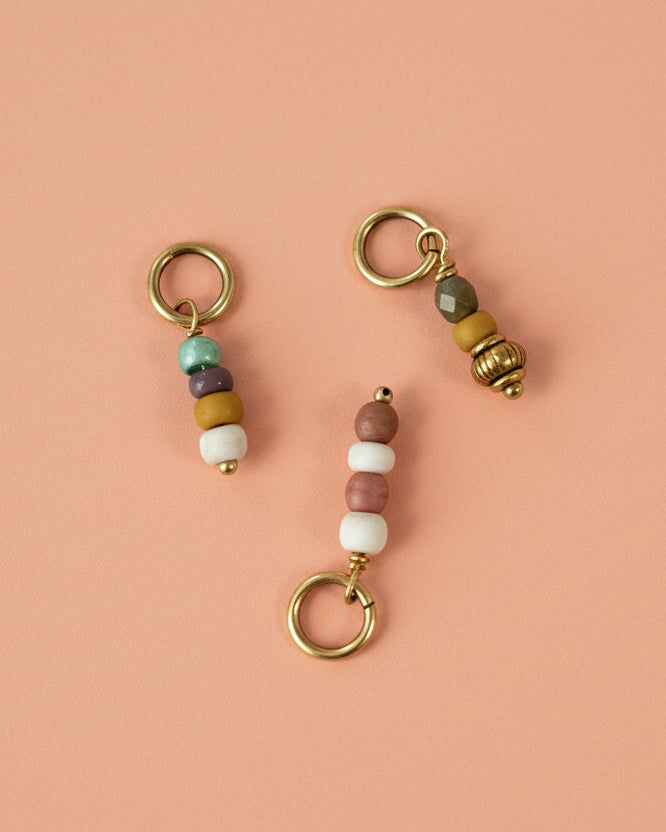 Three beaded keychains on a textured fabric background