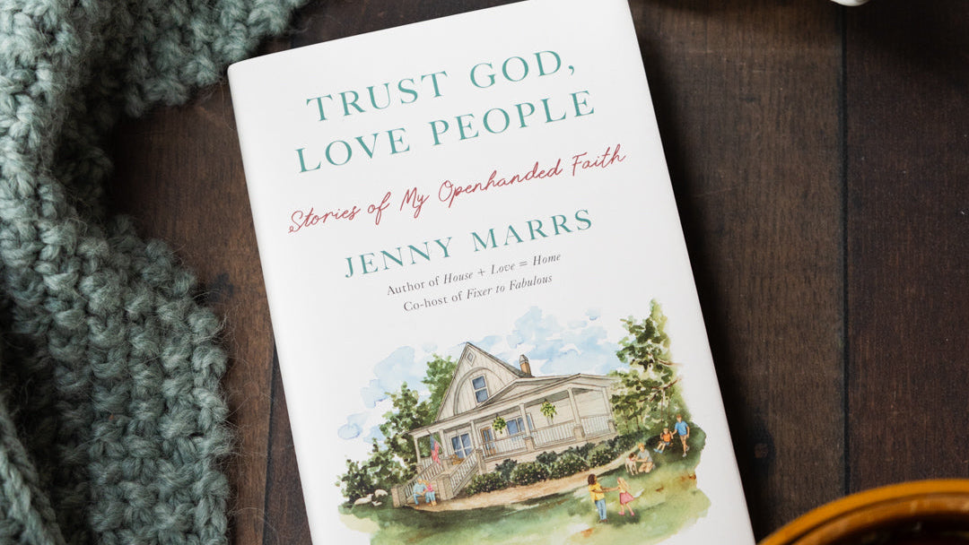 Book titled 'Trust God, Love People' by Jenny Marrs with a cup of coffee and apples on a wooden surface.