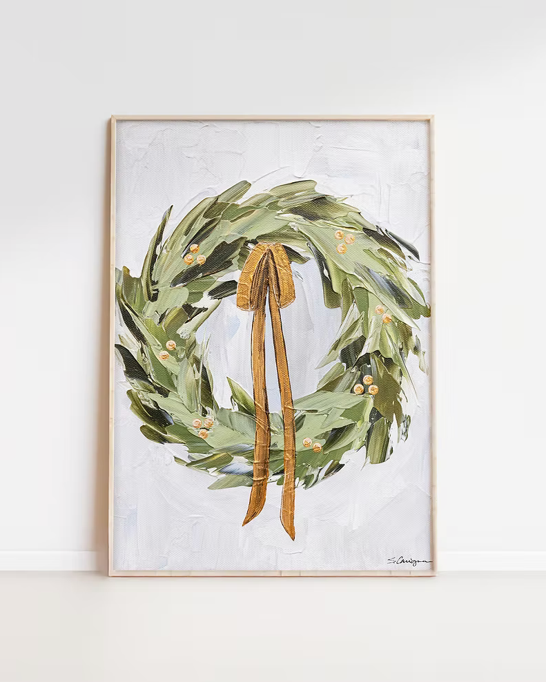 Framed artwork of a green wreath with a brown ribbon on a white background