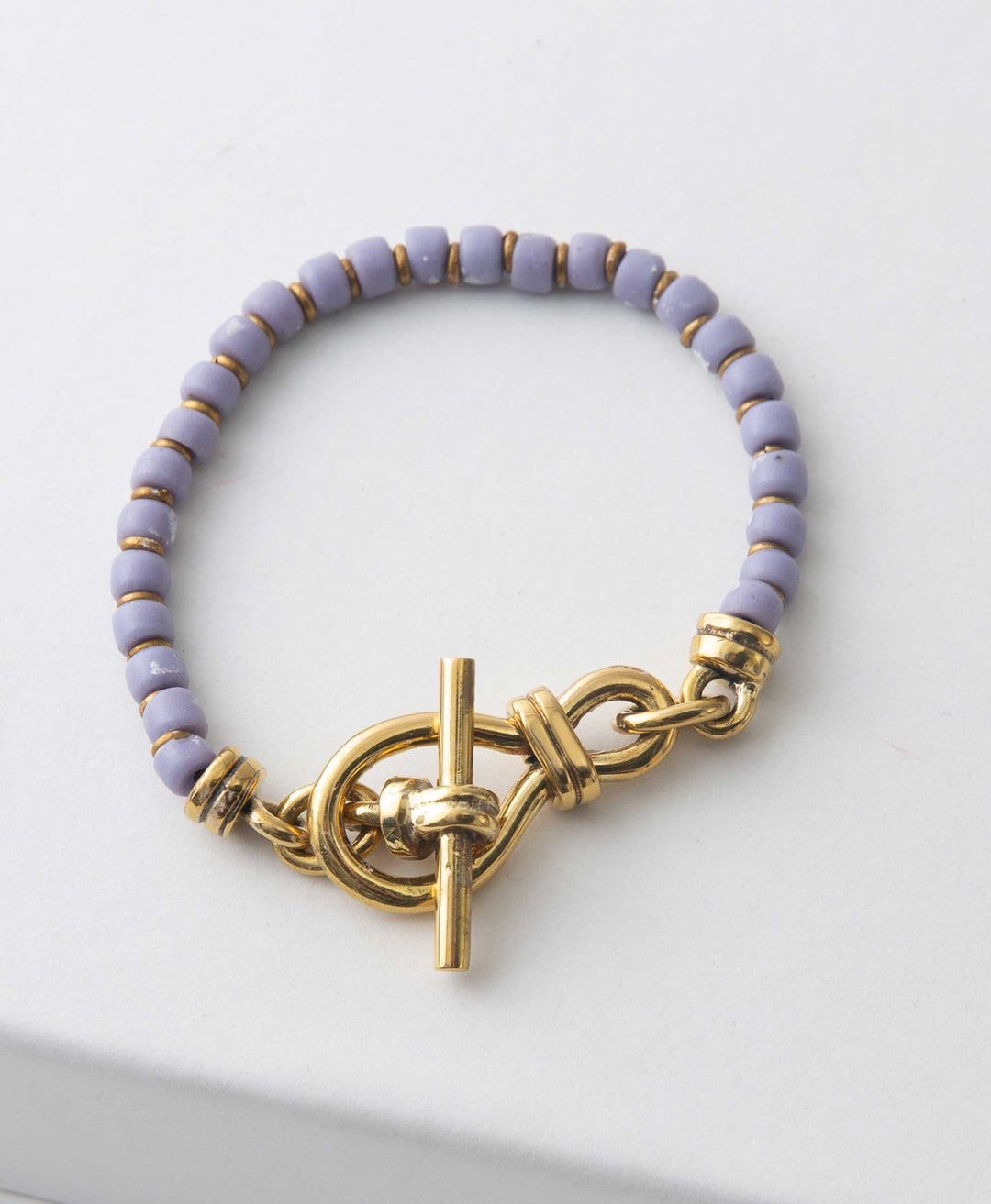 A bracelet with periwinkle blue Turkana beads and a decorative knotted gold clasp.