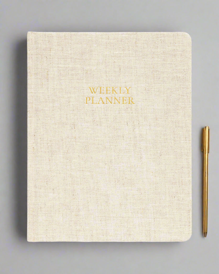 Beige planner with 'Weekly Planner' text in gold on a white background
