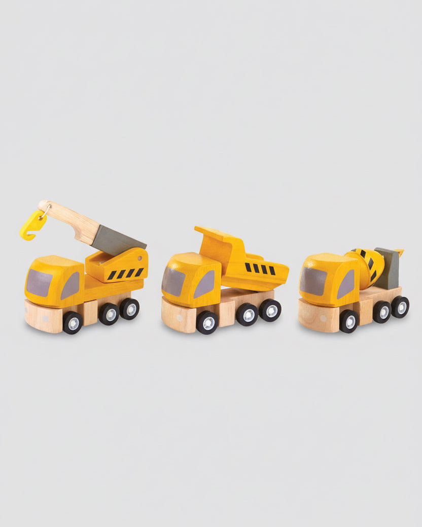 A set of toy trucks including a dump truck, a cement mixer truck, and a crane, all in yellow with black accents, displayed on a wooden surface.