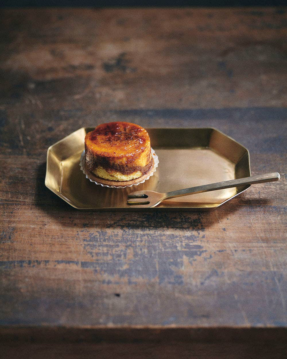 Small dessert on a gold plate with a fork on a wooden surface