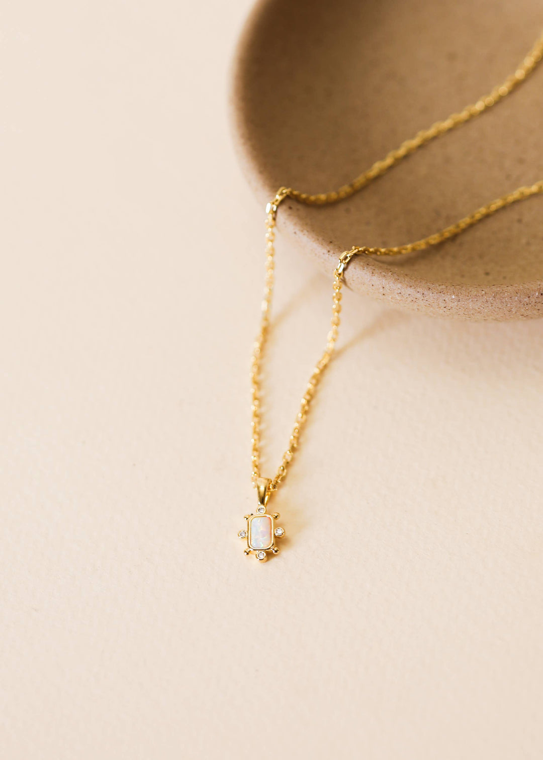 Gold necklace with a pendant on a beige background