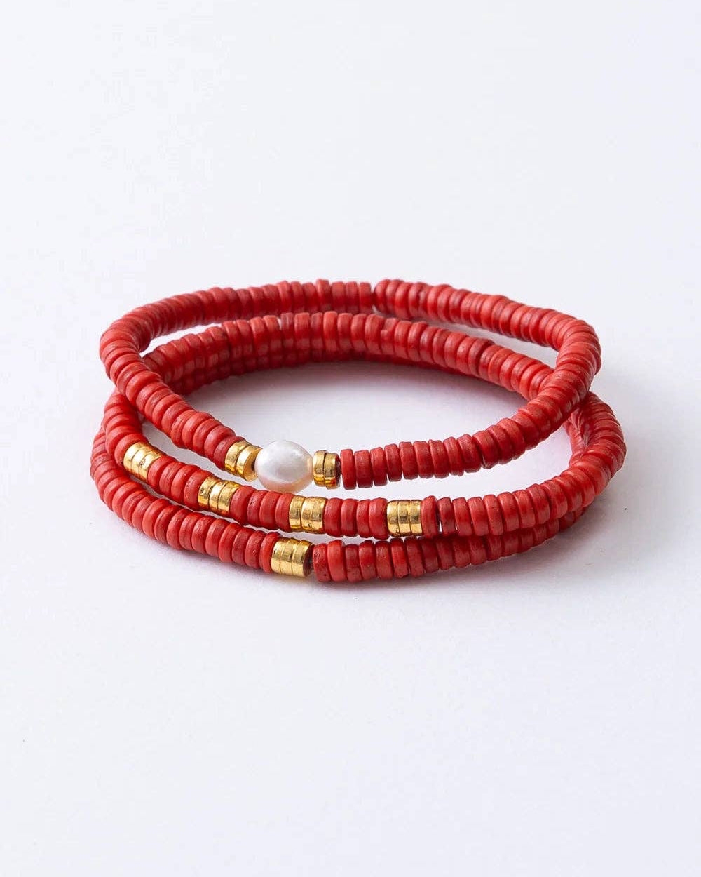 A stack of three red beaded wrap bracelets with small gold spacer beads and a white pearl accent, displayed on a clean white background.