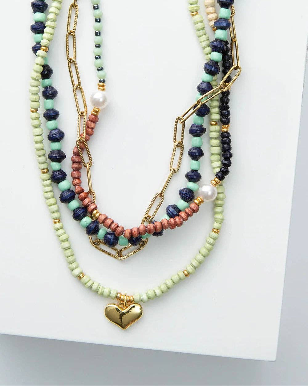 Set of colorful beaded necklaces with heart charm on a white surface