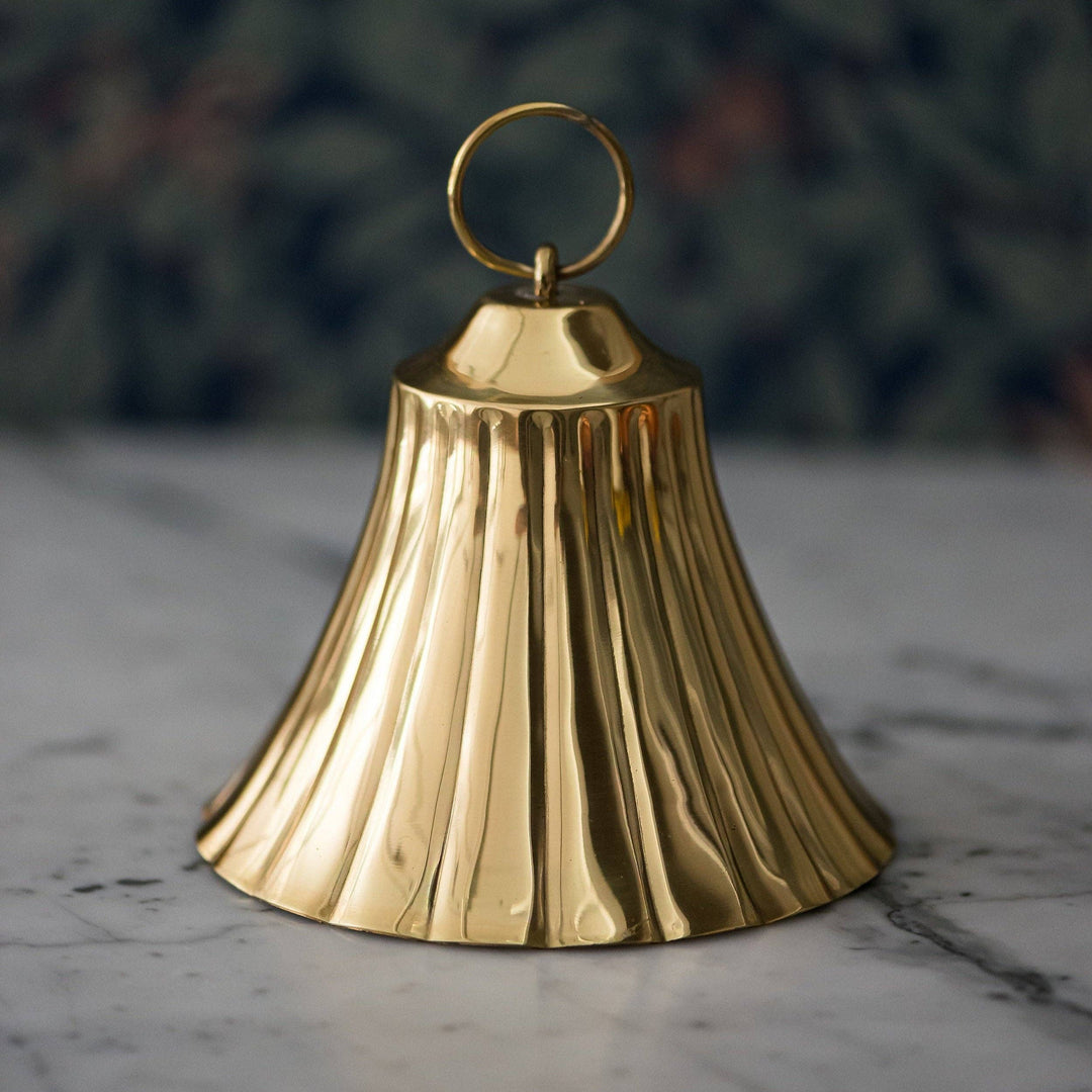 Gold bell on a marble surface with a blurred green background