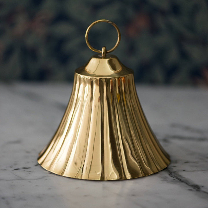 Gold bell on a marble surface with a blurred green background